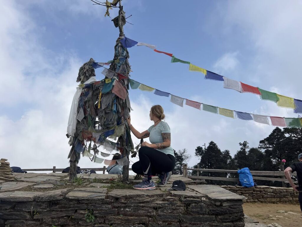 Manouk Schipper bij gebedsvlaggen op een bergtop in Nepal